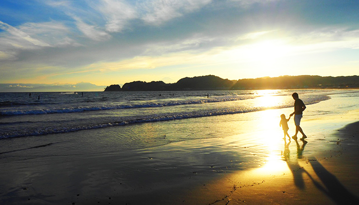 Walking along the beach while watching sunset in the early evening.