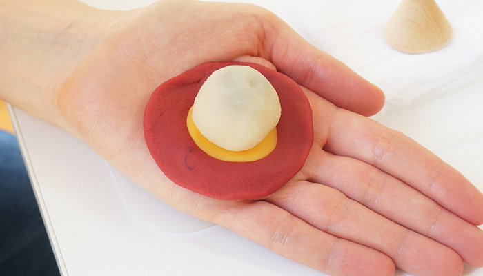 Flatten the red and yellow doughs into circles and stack them on the palm of your hand.